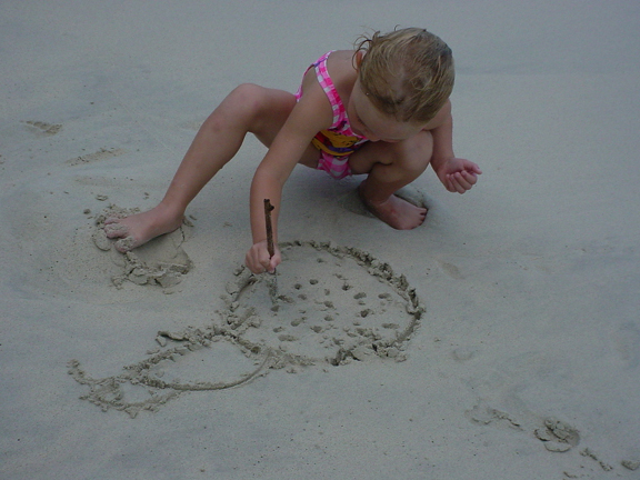 Miranda draws her favorite lady-bug portrait in the sand.